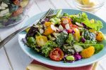 Fresh organic super food salad sitting on blue plate with fork on side.