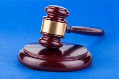 Wooden brown judges gavel on blue table.