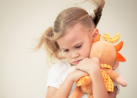 little girl cuddling orange soft toy