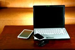 Laptop computer, mobile phone and a tablet on a table.