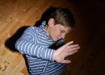 Boy in Dim Room with Hands in Front of Face