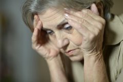 POld woman holding her head in her hands.