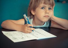 5 year old boy dreaming while doing his maths homework.