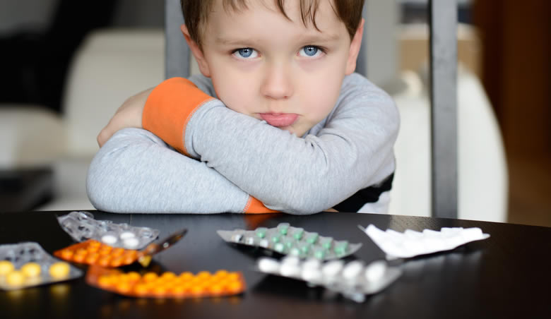 Cross boy in front of pills.