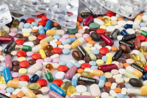 Pharmaceutical multi-colored tablets and capsules scattered on the surface.