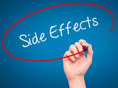 A man's hand writing side effects on a screen.