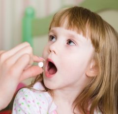 Small girl taking a pill.